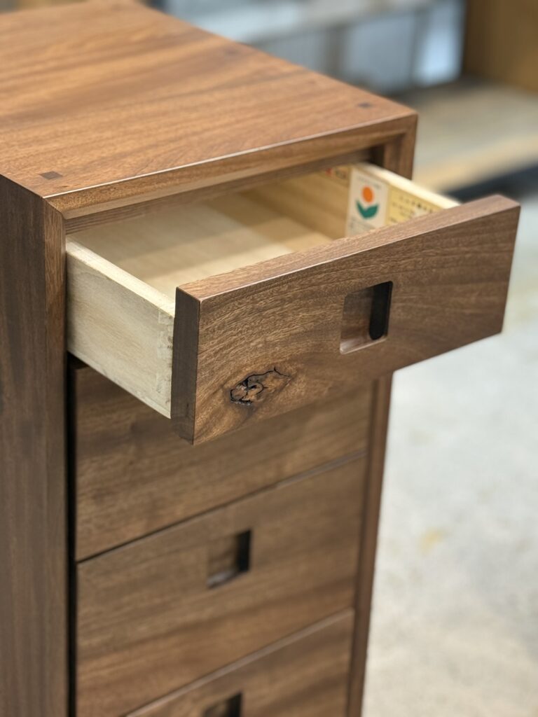 Shinra（シエラ）楠無垢材 340-4段チェストの引き出しと取手のディテール写真。無垢材の滑らかな質感と金属取手の精巧な仕上げが際立つ収納家具の部分アップ。