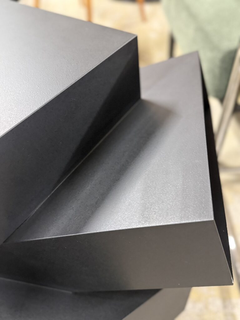 Porro（ポロ）Balancing Boxes（バランシング・ボックス）収納ユニット。メタルブラックの不規則に配置された木質ボックス構成で、光を抑えたマットな質感とシャープな陰影が際立つミニマルモダンデザイン。