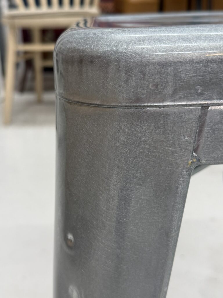 TOLIX(トリックス)H45 Stool 座面画像。職人がメタルシートを折り曲げ溶接した跡や、グラインダーによる研磨で生まれた荒々しいヘアライン(擦れ跡)が残る無骨な金属質感が特長。