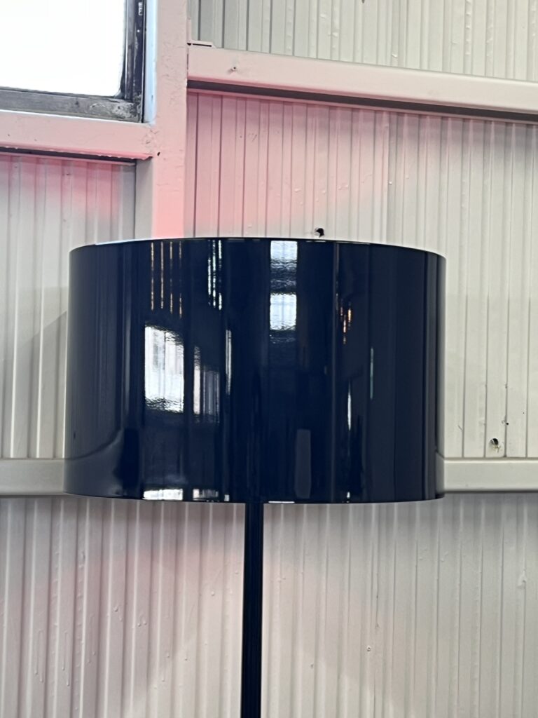FLOS（フロス）SPUN LIGHT F フロアランプ。光沢のあるグロスブラックのアルミニウム製シェードが、マットな黒とは異なる存在感を放ち、内側のホワイトが柔らかな光を広げる。